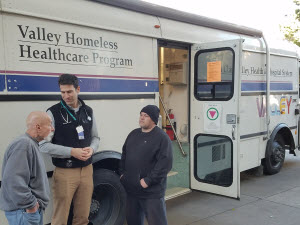 Two medical assistants helping a homeless man